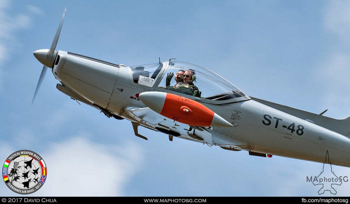 25. Pilots of the Belgian Air Force SF.260 (ST-48) waves crowd as it performs a low pass.