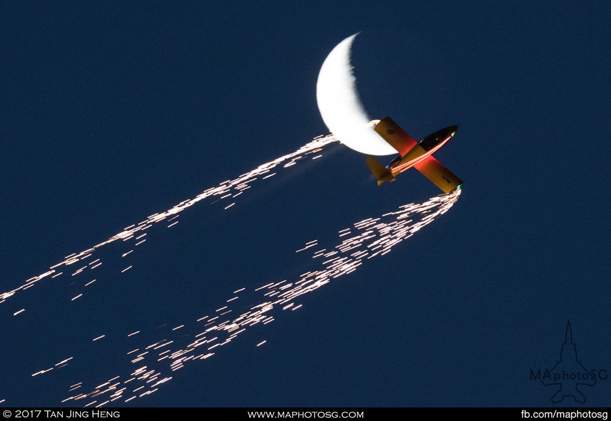 Performing in front of a crescent moon, the JX2 SubSonex Microjet powers through the night sky with fireworks during Avalon 2017