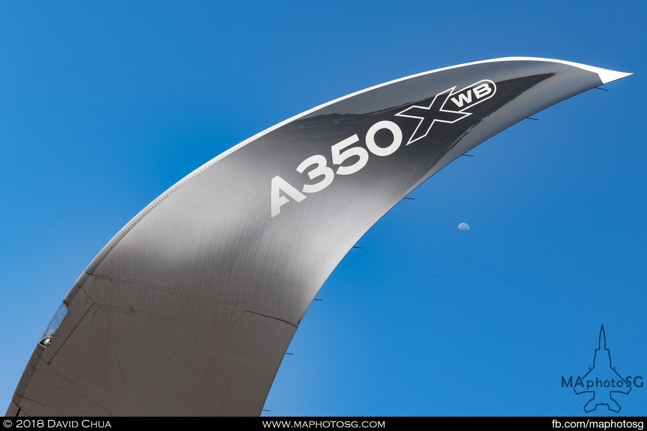 The moon sets under the curved winglet of the Airbus A350-1000