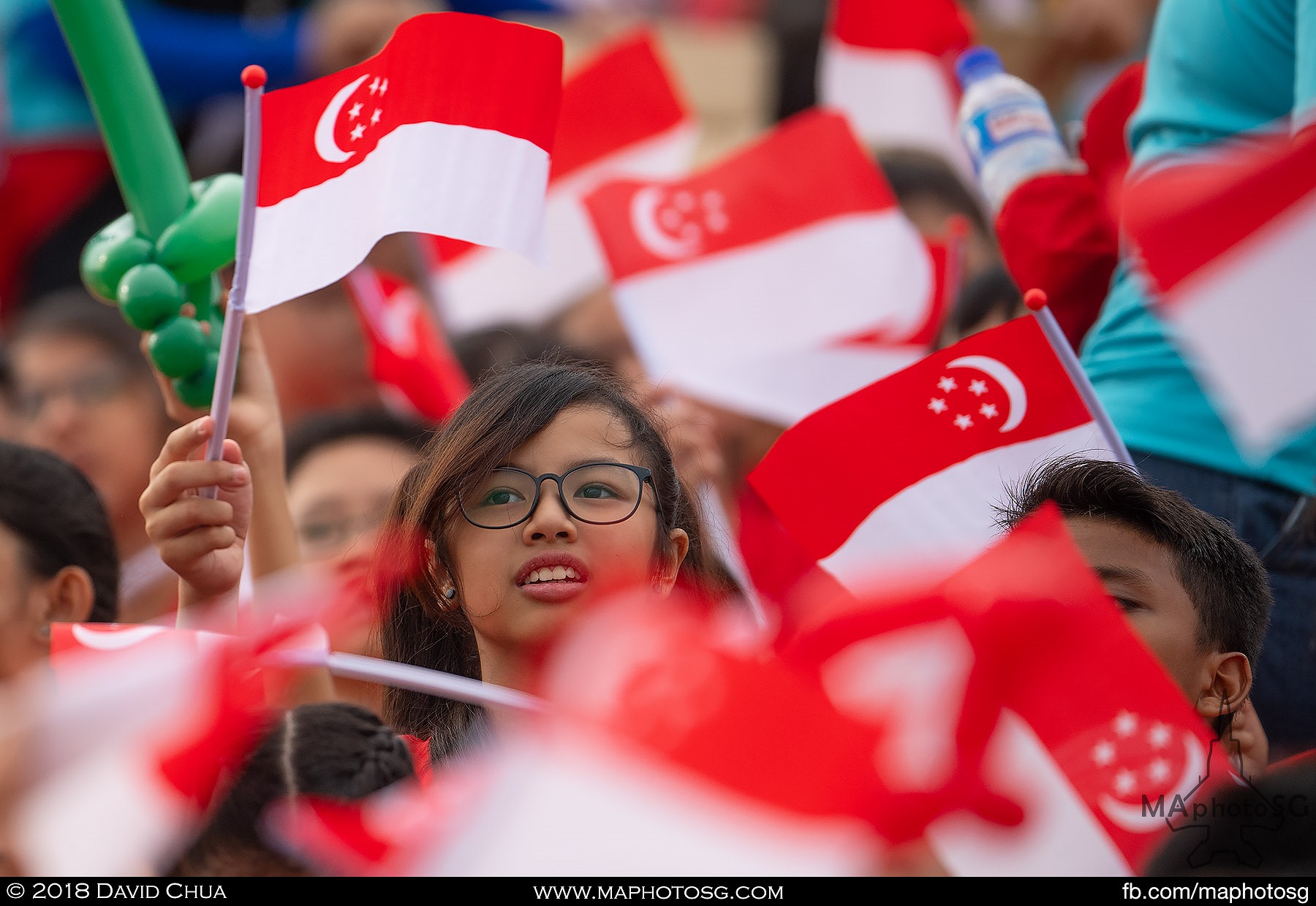 01. A girl waves the Singapore Flag amidst a sea of flags.