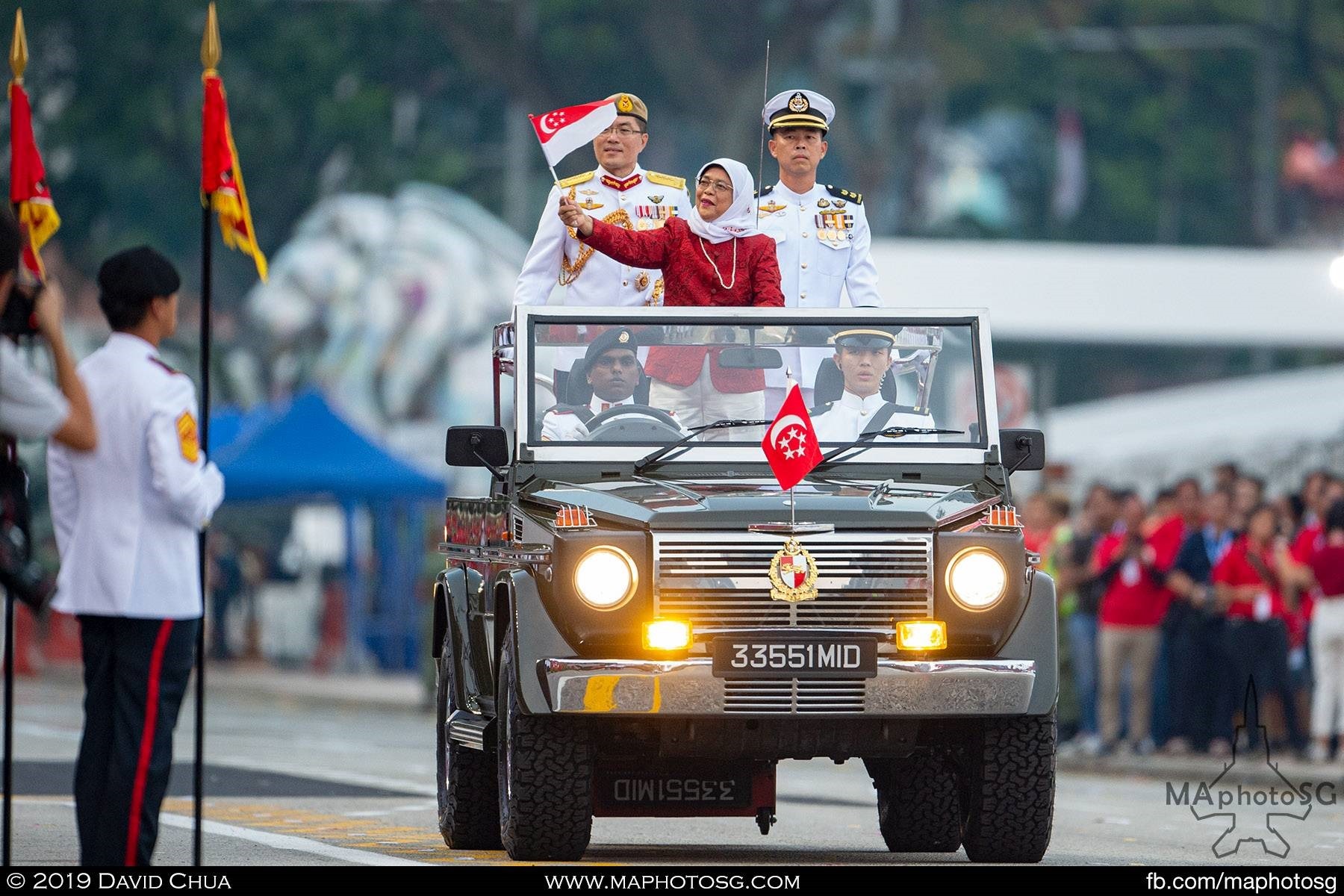 President Halimah Yacob waves to the crowd as she goes around the Padang in a ceremonial land rover
