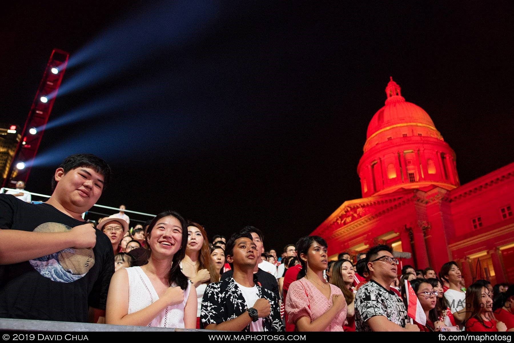 Spectators in blue sector reciting the national pledge at the finale of NDP2019