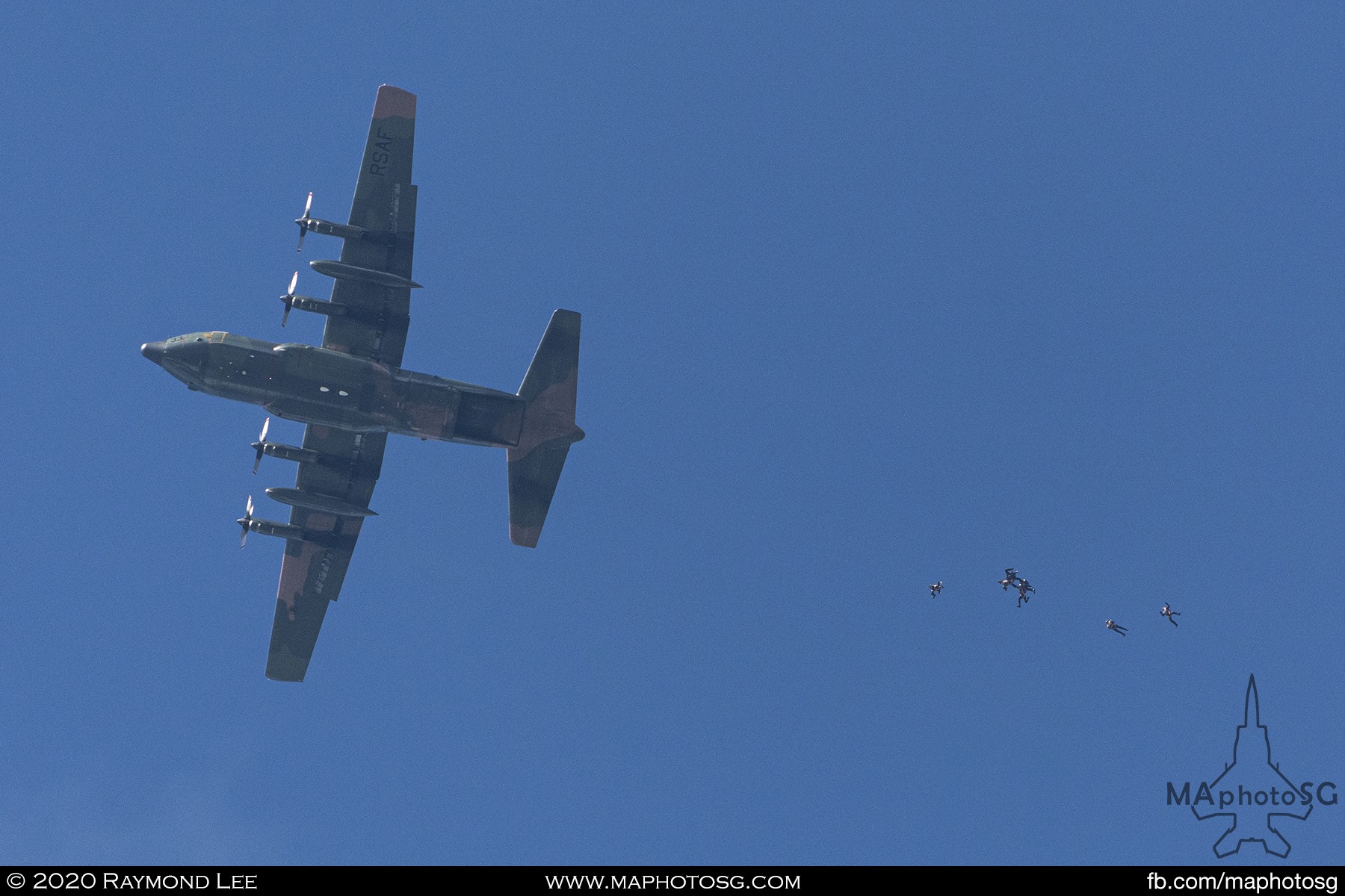 The Singapore Armed Forces Red Lions Freefall team jump out of a RSAF C-130H Hercules to begin their descent.