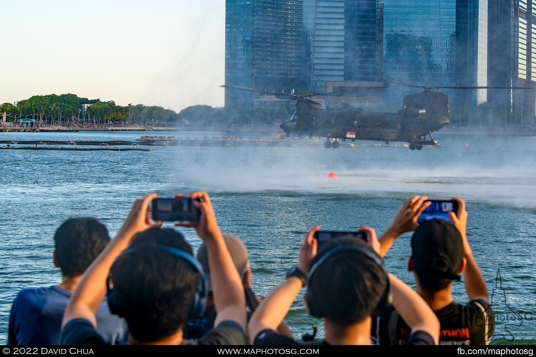 The crowd along Esplanade Waterfront capturning the Chinook hovering about the water deploying Navy divers