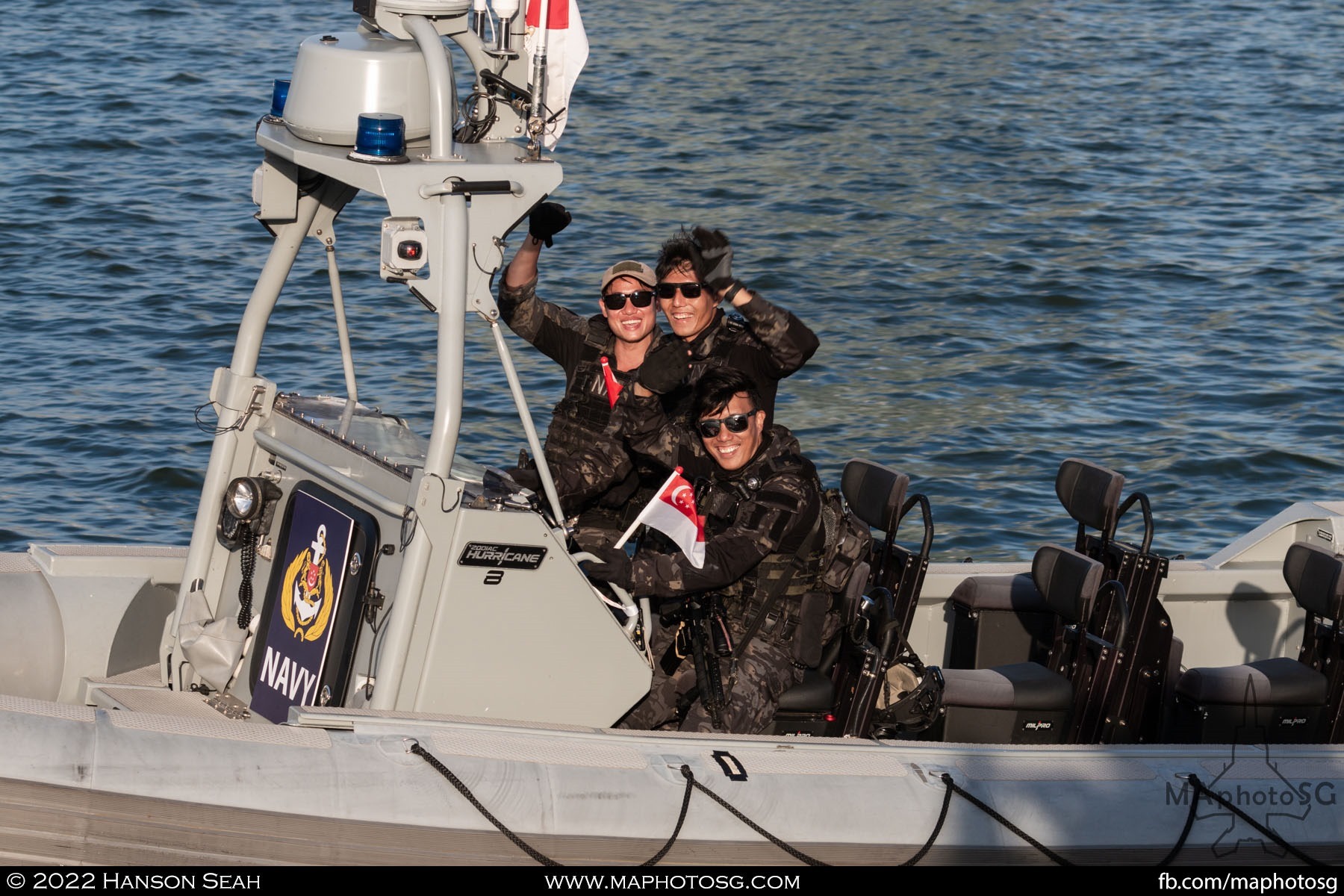 Navy servicemen waves to the crowd around the Marina Bay area after the complete their performance