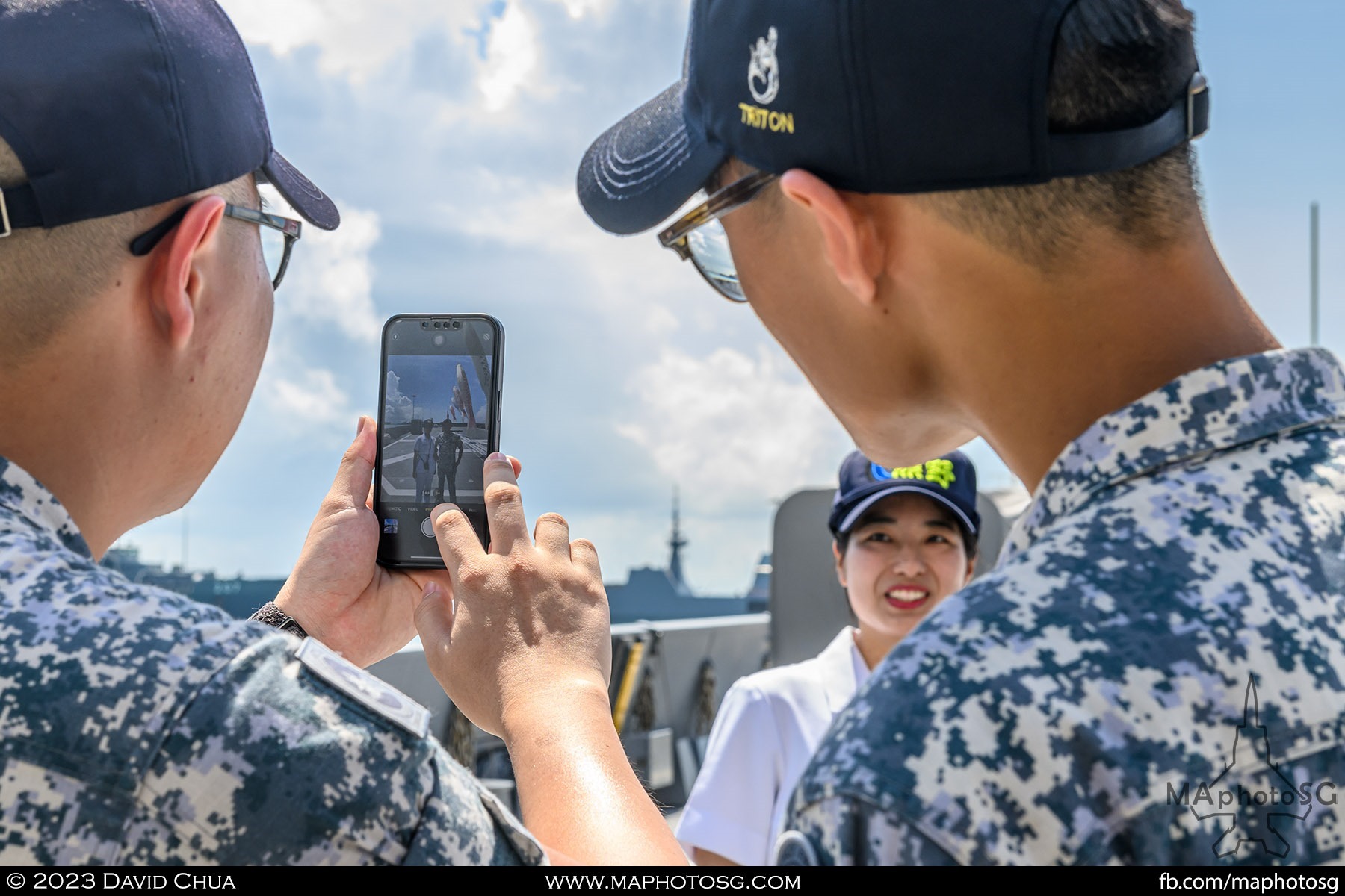 Visiting sailors taking pictures with a beautiful crew member of the JS Kumano