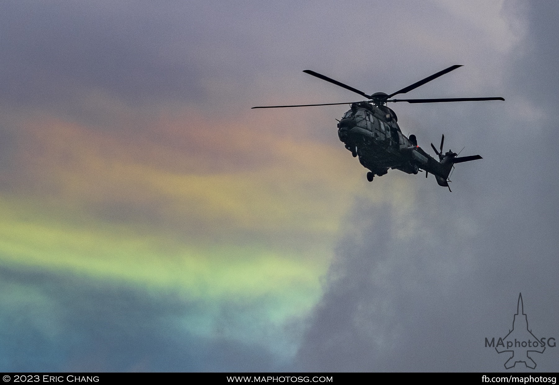 RSAF's H225M flies into show centre under a backdrop of iridescent clouds.